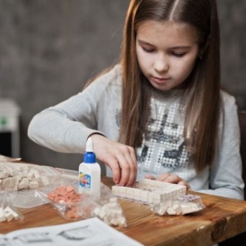 дівчинка збирає керамічний конструктор з міні цеглинок